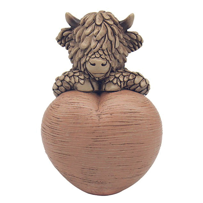 Hughie the Highland Cow, sitting on a heart ornament