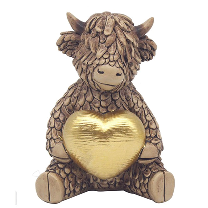Hughie the Highland Cow, sitting on a golden heart ornament