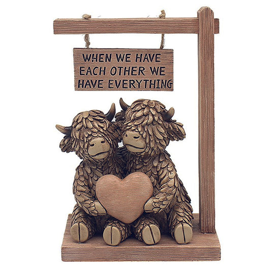 Hughie the Highland Cow couple under sign reading When We Have Each Other, We Have Everything