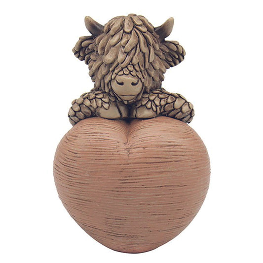 Hughie the Highland Cow, sitting on a heart ornament